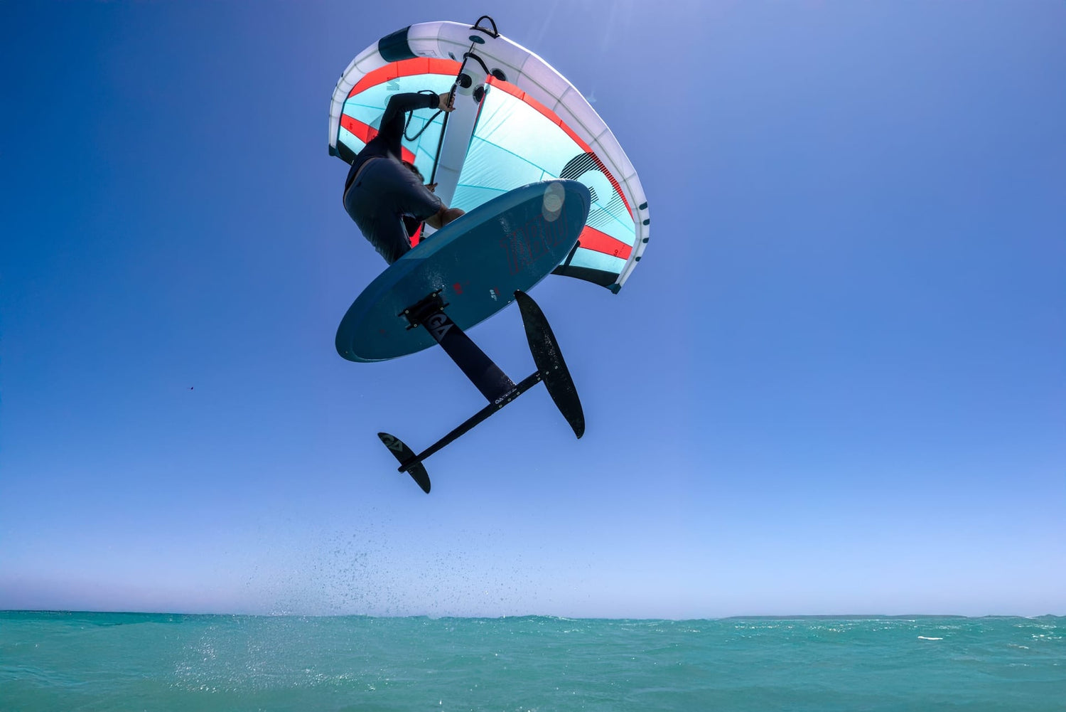 A person wingfoiling on a GA Wing Poison and a Tabou wingfoil boar