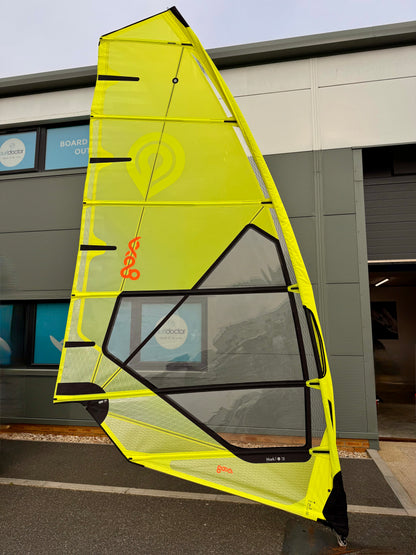 Yellow Goya windsurf sail with Surfdoctor shop branding against a building background