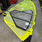 Yellow and black windsurf sail on a concrete floor with storage items in the background