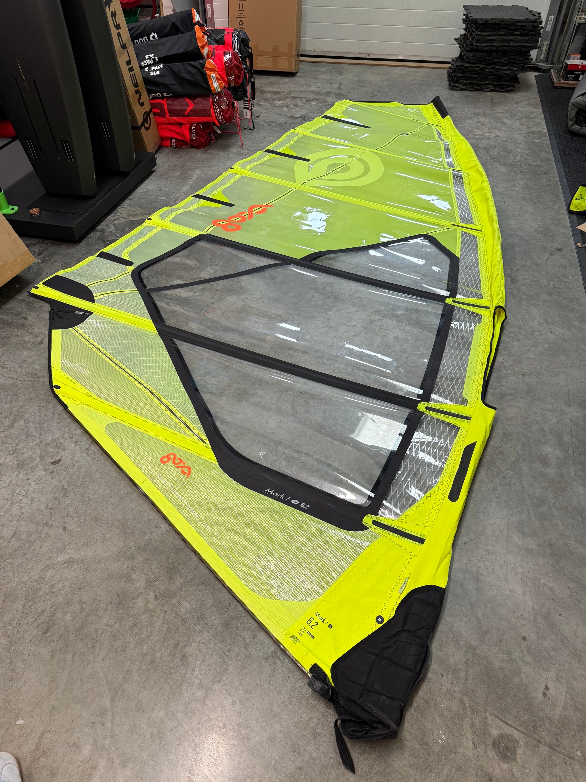 Yellow and black windsurf sail on a concrete floor with storage items in the background
