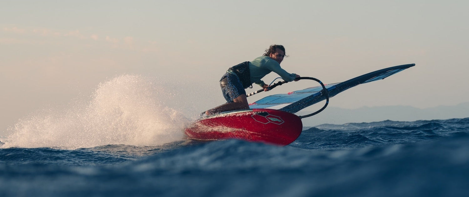 Person windsurfing on a red tabou board with a GA Brand sail in the ocean